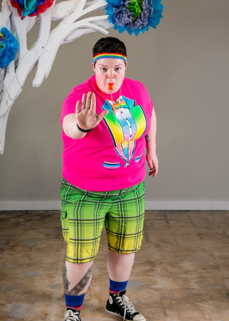 Lesbian gym coach with brightly colored clothes, a whistle, standing posing for her prom photo.