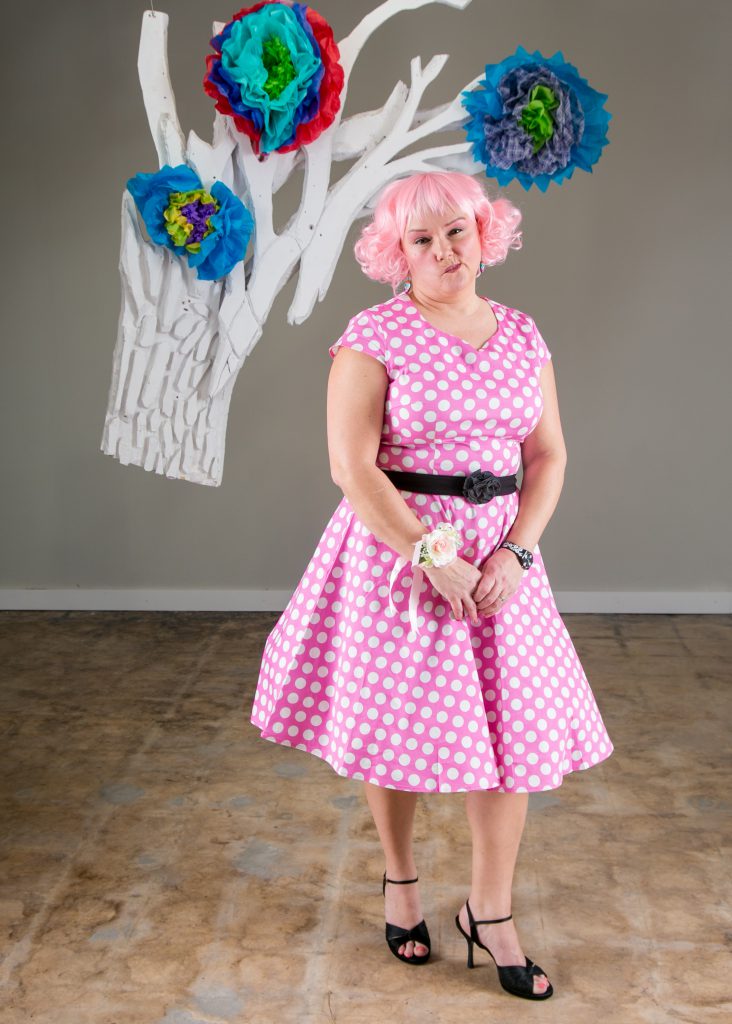 Cute girl in polka dot dress posing for prom photo.